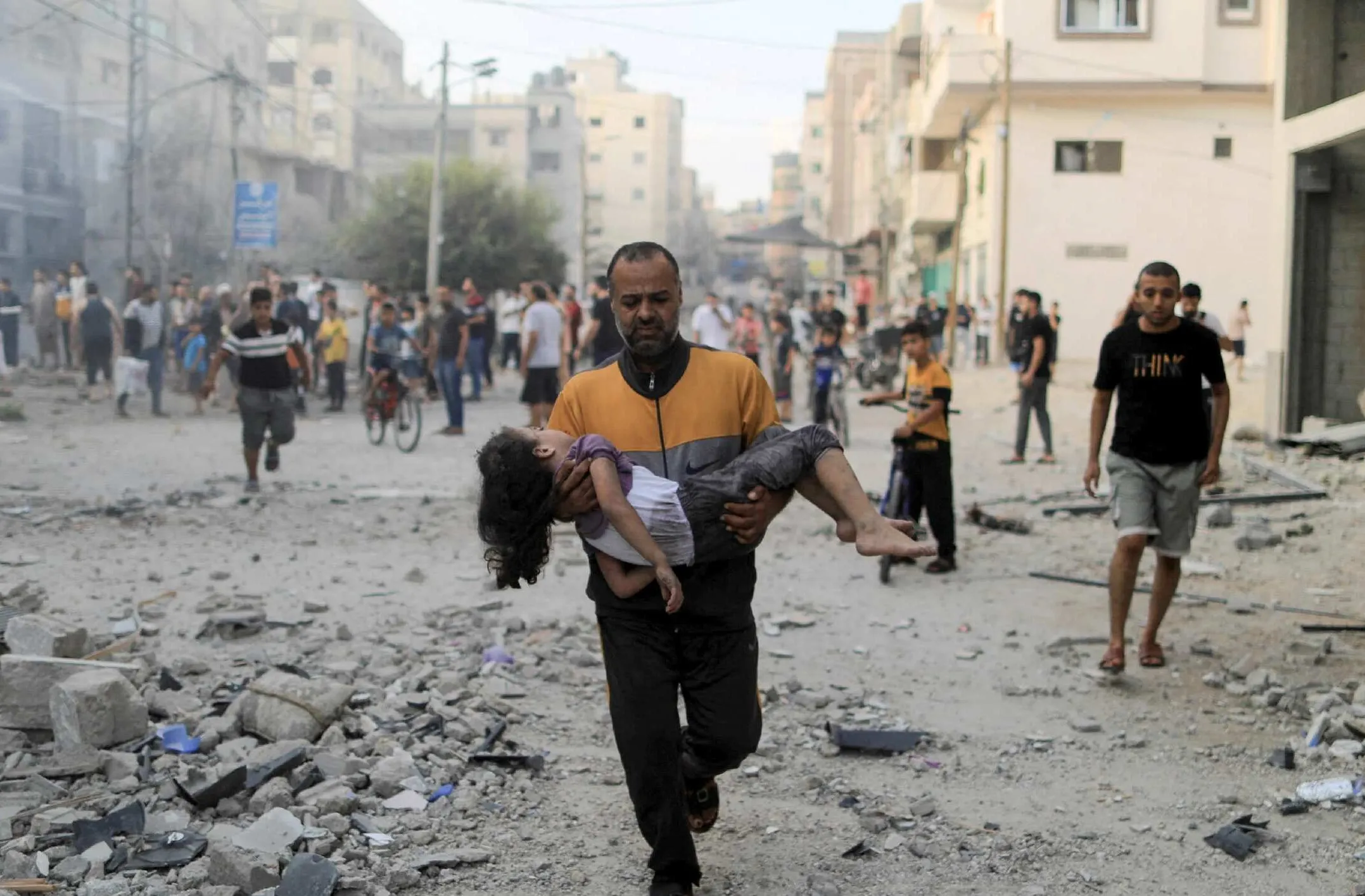 A Palestinian man carries a wounded girl after Israeli strikes in Khan Younis in the southern Gaza Strip [Yasser Qudih/Reuters]